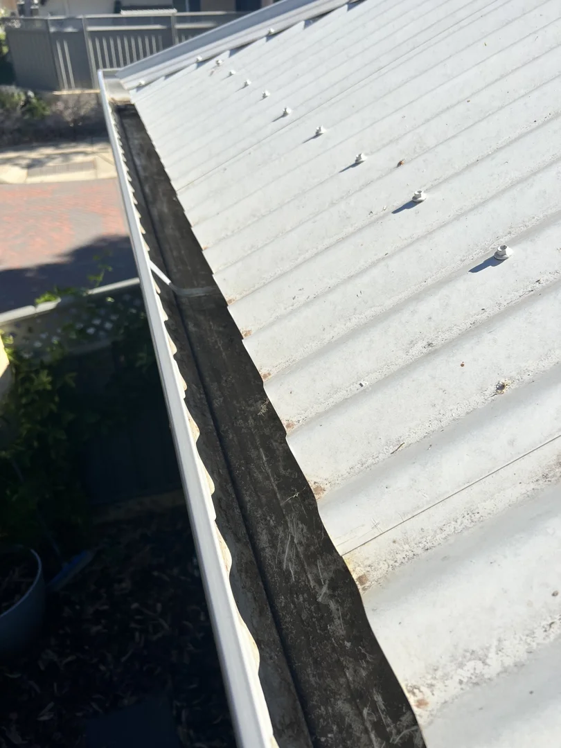 Same metal roof gutter after cleaning — channel completely cleared of debris.