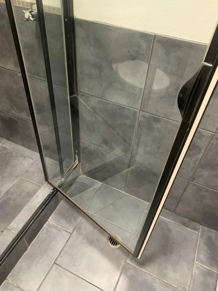Same shower door after cleaning — glass crystal clear with no soap scum and tiles fully visible.