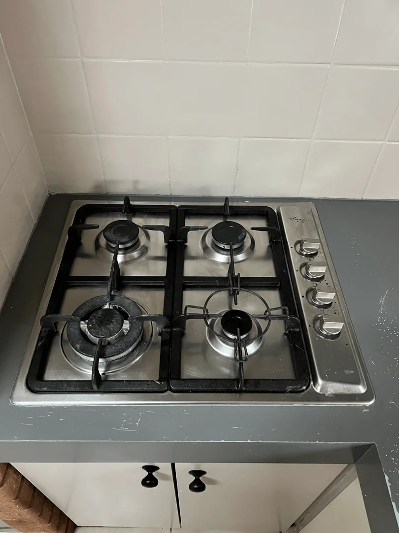 Same stainless steel stovetop after cleaning — surface scrubbed to a high-shine, reflective finish with clean grates.